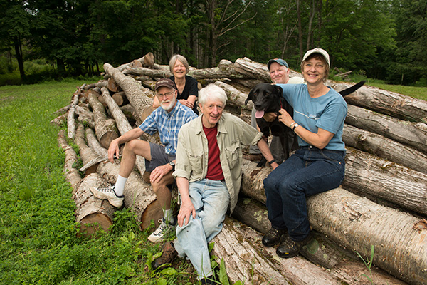 happy people and a dog sitting on a pile of logs